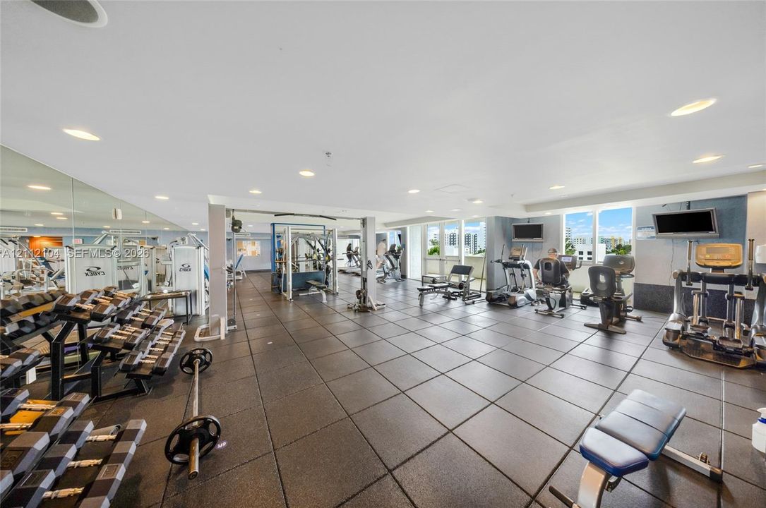 Fitness center featuring rubberized tile flooring, mirrored walls, recessed lighting, and expansive floor-to-ceiling windows