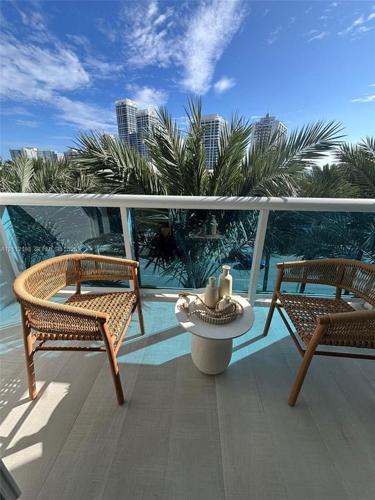 Private balcony featuring wood-finish flooring and a tempered glass railing