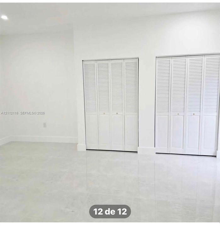 Neutral interior featuring light-toned tile flooring, white walls, and two sets of white louvered closet doors