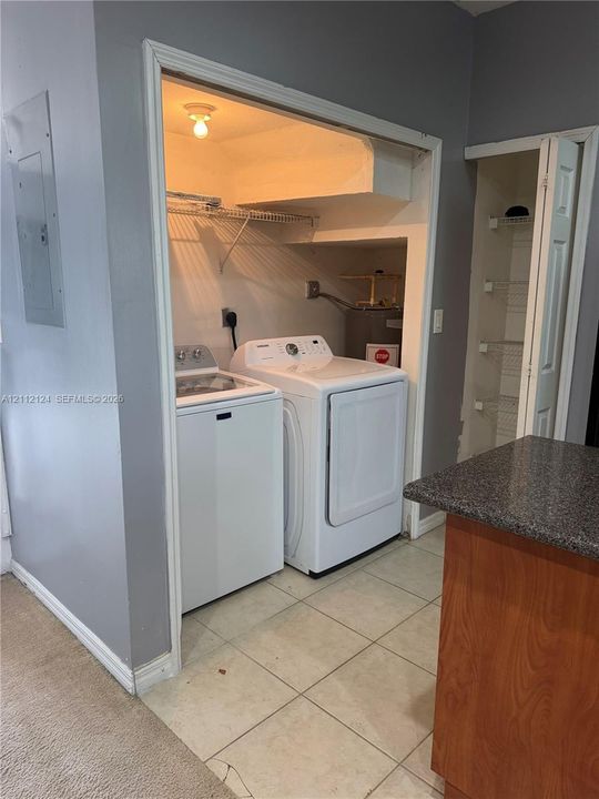 Laundry alcove featuring a recessed built-in wire shelving system, overhead lighting, and an additional adjacent reach-in closet with built-in storage