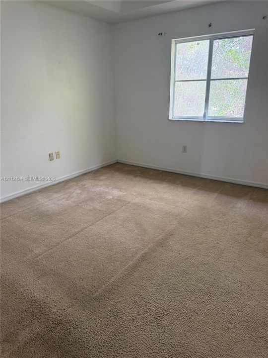 Neutral-toned wall-to-wall carpeting, single-pane window with muntins, and textured ceiling