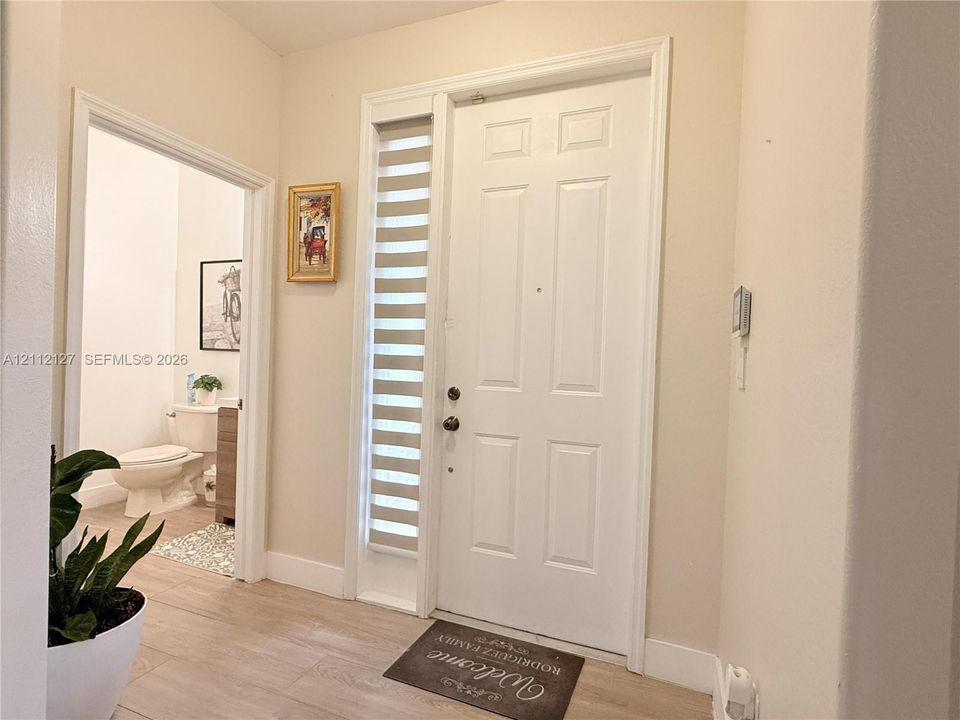Entryway featuring a six-panel white door with vertical sidelight window and wood-finish flooring