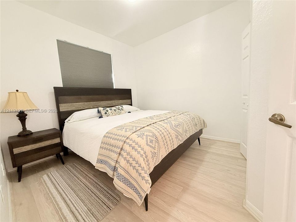 Neutral-toned wall finish, wood-finish flooring, and a window with a fitted cellular shade