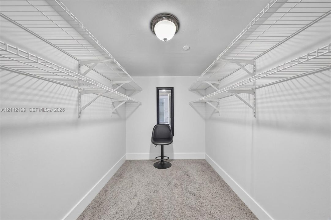 Walk-in closet featuring dual-tier white wire shelving, wall-to-wall carpeting, and a flush-mount ceiling fixture