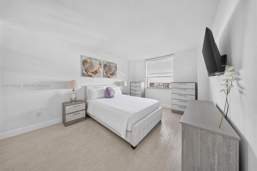 Neutral-toned wood-finish flooring and large window with integrated horizontal blinds