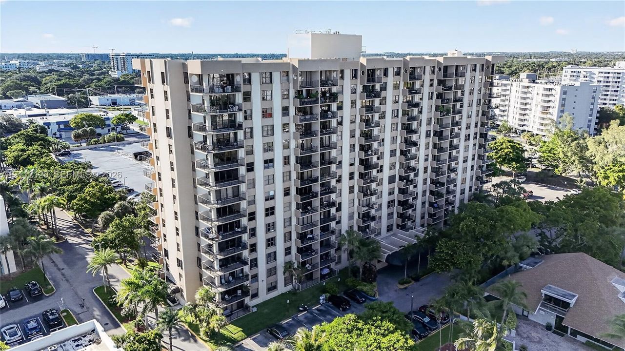 High-rise residential building featuring stacked private balconies, a multi-story concrete facade, and an attached covered entrance canopy