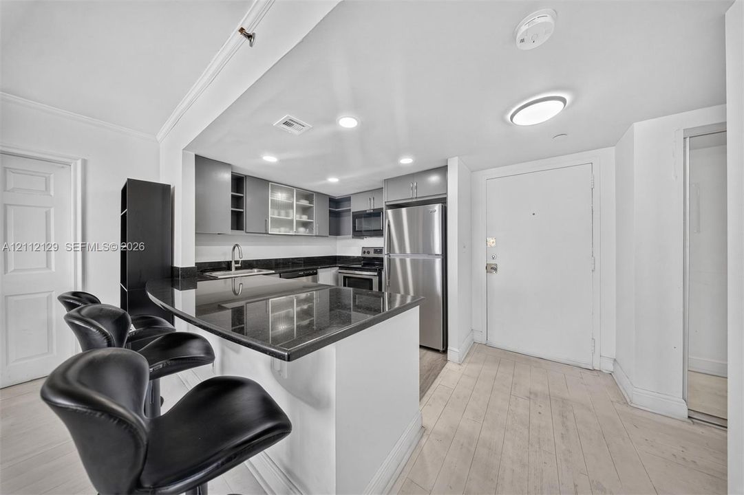 Kitchen featuring grey cabinetry, dark stone-finish countertops, stainless steel appliances, recessed lighting, and wood-finish flooring