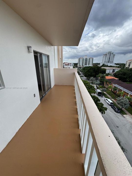 Covered balcony featuring smooth concrete flooring, solid masonry walls, and a white metal safety railing