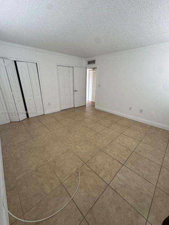 Interior space featuring large-format tile flooring and multiple bi-fold door closets