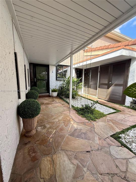 Spacious living area featuring diagonal-set tile flooring, expansive built-in white cabinetry, recessed lighting, and large sliding glass doors