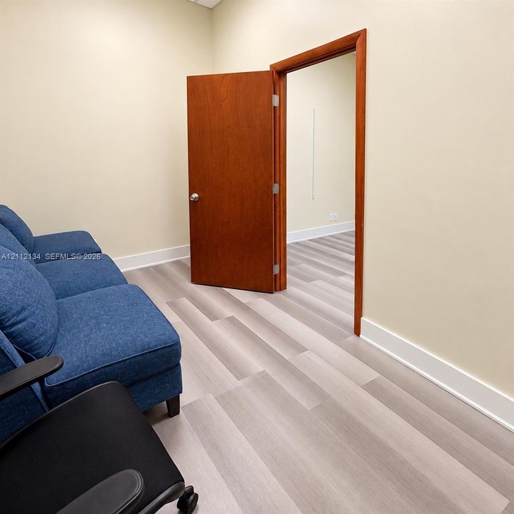 Wood-finish flooring, neutral wall tones, and solid wood-finish door with matching frame