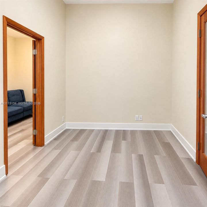 Wood-finish flooring with neutral wall tones, complemented by solid wood door frames and an installed glass-panel door