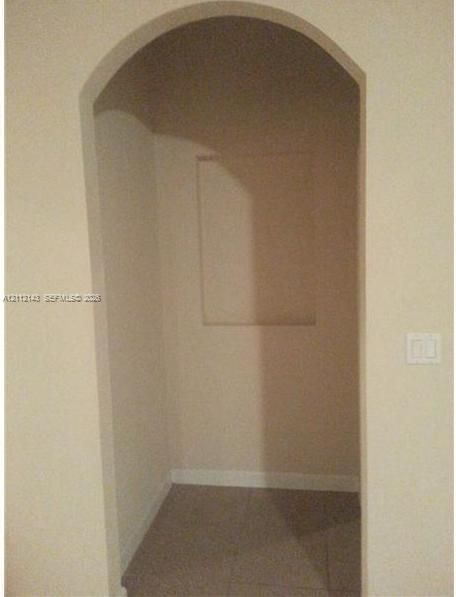 Arched entryway featuring a recessed wall niche and neutral-toned flooring