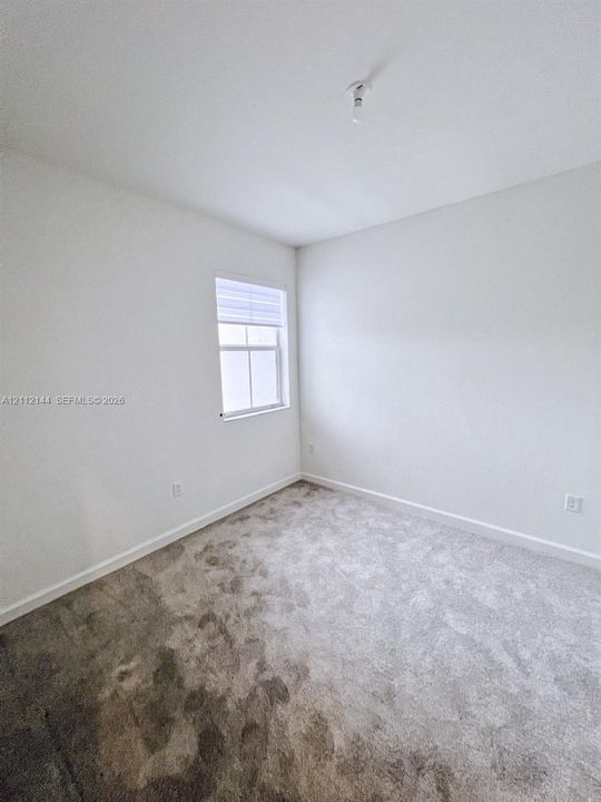 Neutral-toned carpeted flooring, white wall finishes, and a single window with fitted blinds