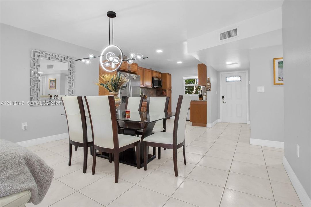 Open concept floor plan with tile flooring, recessed lighting, modern circular chandelier, and kitchen cabinetry