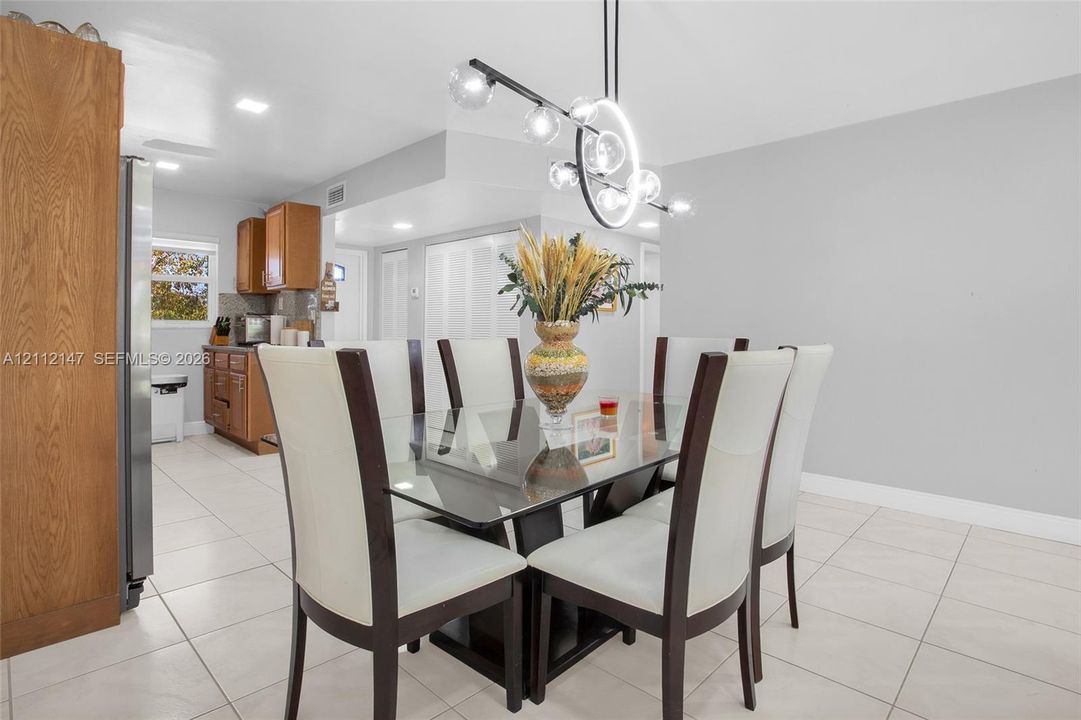 Dining area featuring large-format ceramic tile flooring, a modern multi-globe chandelier, and recessed lighting