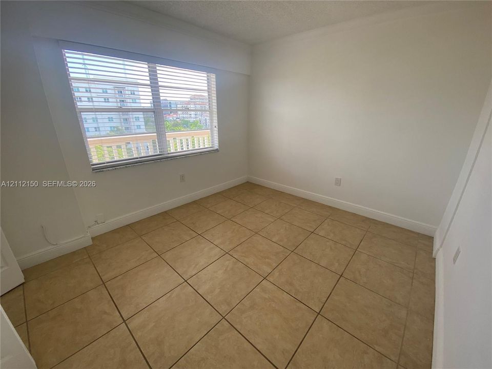 Neutral-toned ceramic tile flooring, expansive window with horizontal blinds, and neutral wall paint