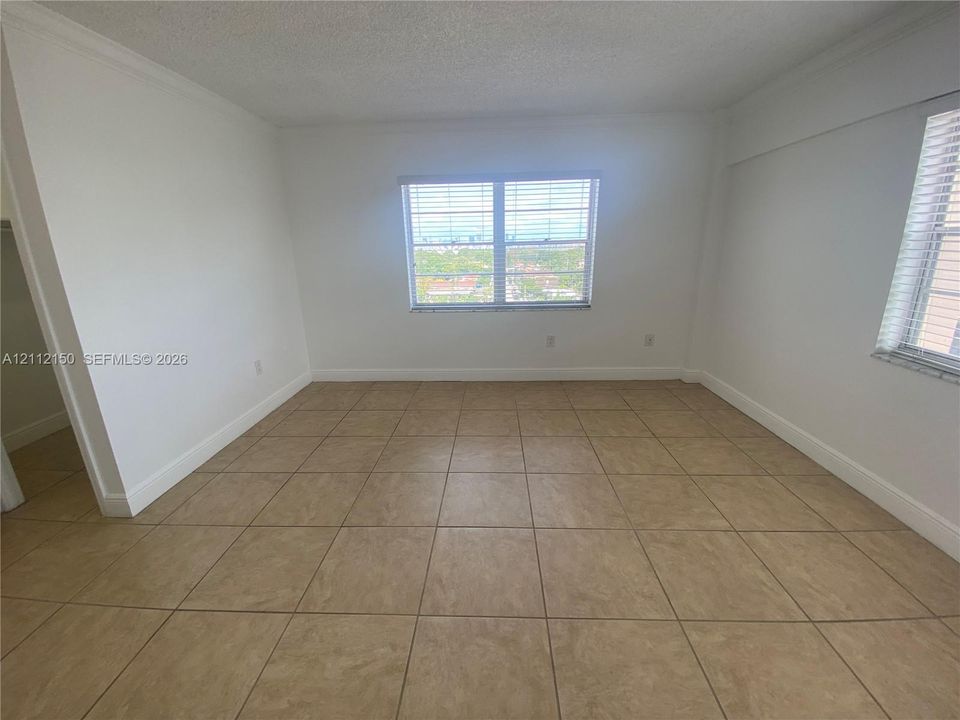 Neutral-toned ceramic tile flooring, dual multi-pane windows with horizontal blinds, and smooth-finish white walls