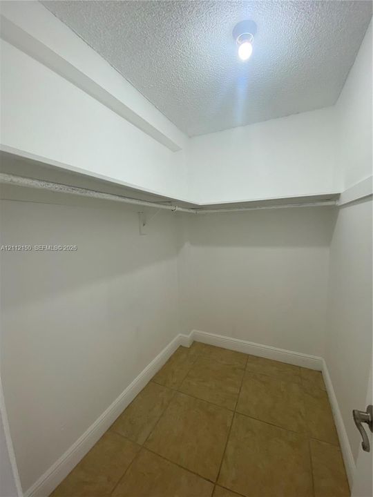 Storage space featuring large-format ceramic tile flooring, built-in shelving, and a ceiling-mounted light fixture