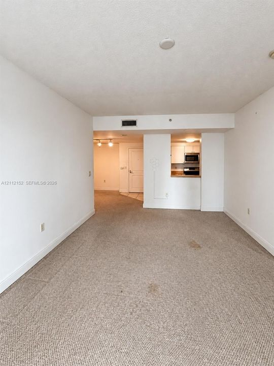 Open interior area featuring wall-to-wall carpeting and a kitchen with built-in cabinetry and integrated appliances