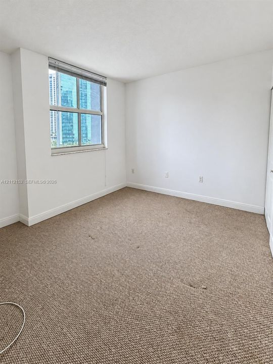 Neutral-toned wall-to-wall carpeting, window with integrated blinds, and closet with sliding doors
