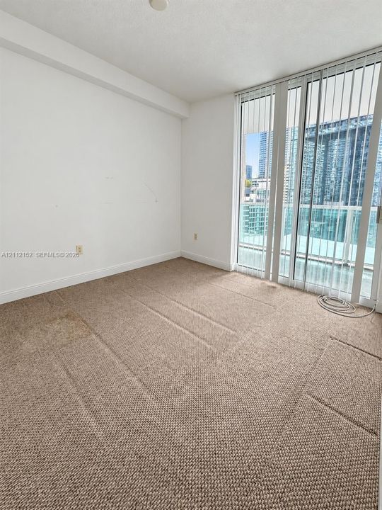 Wall-to-wall carpeting, full-height glass sliding door, and floor-to-ceiling windows with urban outlook