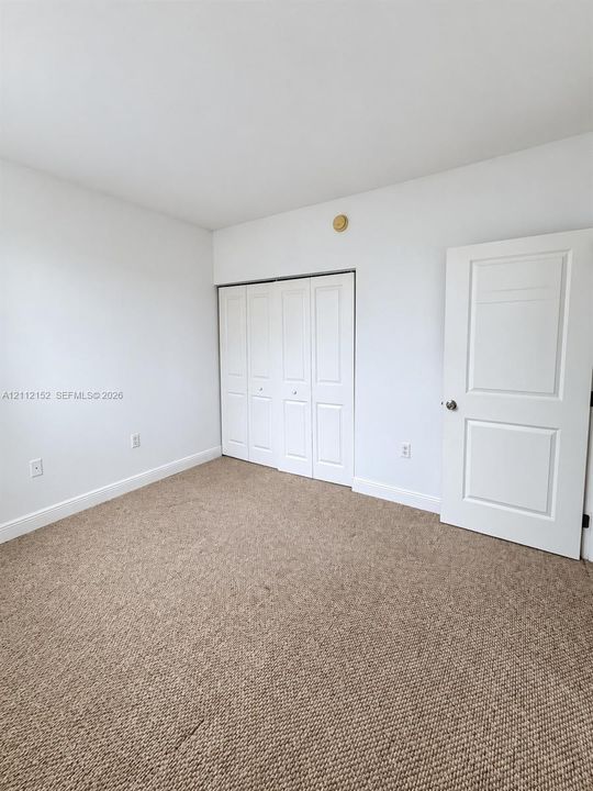 Neutral-toned carpeting, white walls, folding-panel closet doors, and a solid-core two-panel interior door