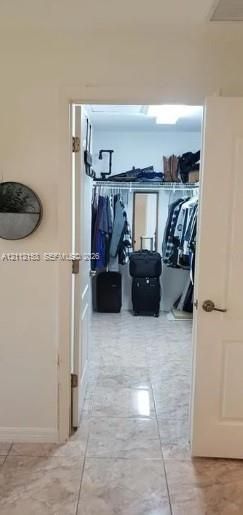 Walk-in closet featuring stone-finish floor tiles, integrated wire shelving, and overhead lighting