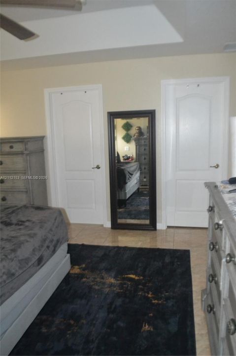 Tray ceiling featuring a recessed center, dual interior arched-panel doors, and neutral tile flooring