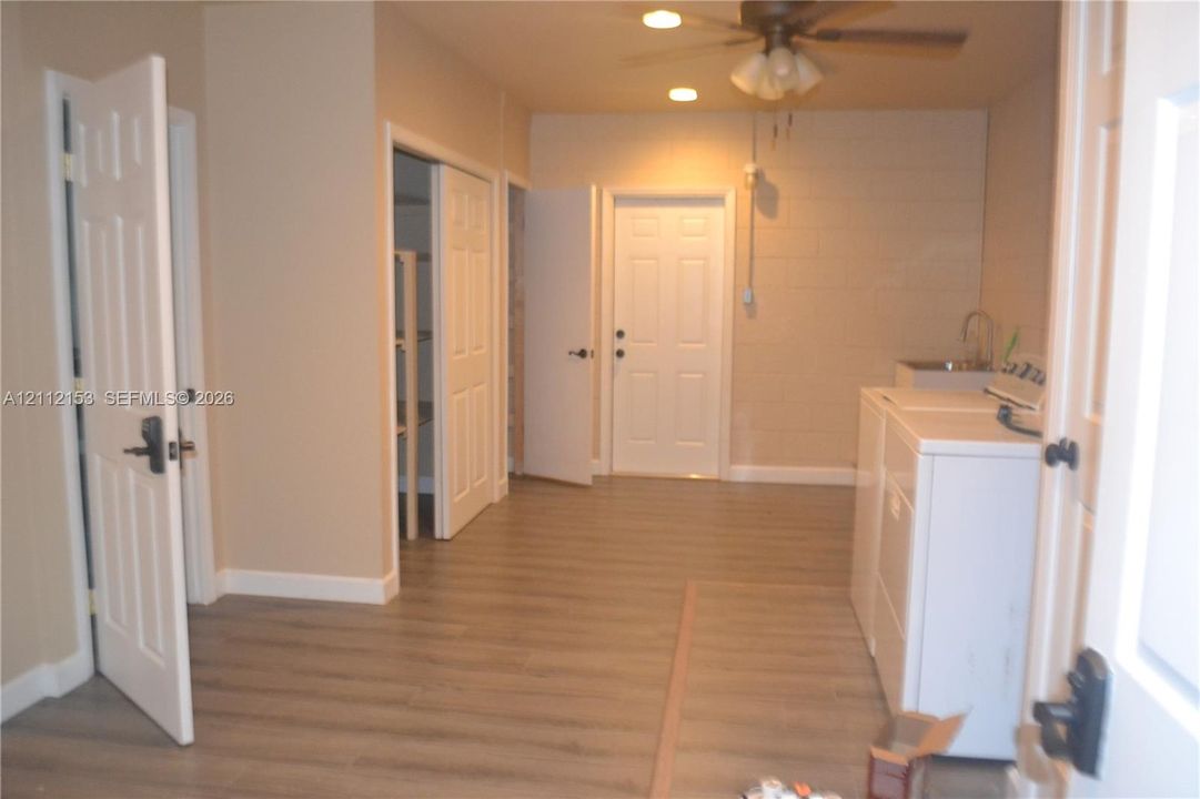 Utility room featuring wood-finish flooring, recessed lighting, ceiling fan, dedicated sink basin, and built-in closet storage