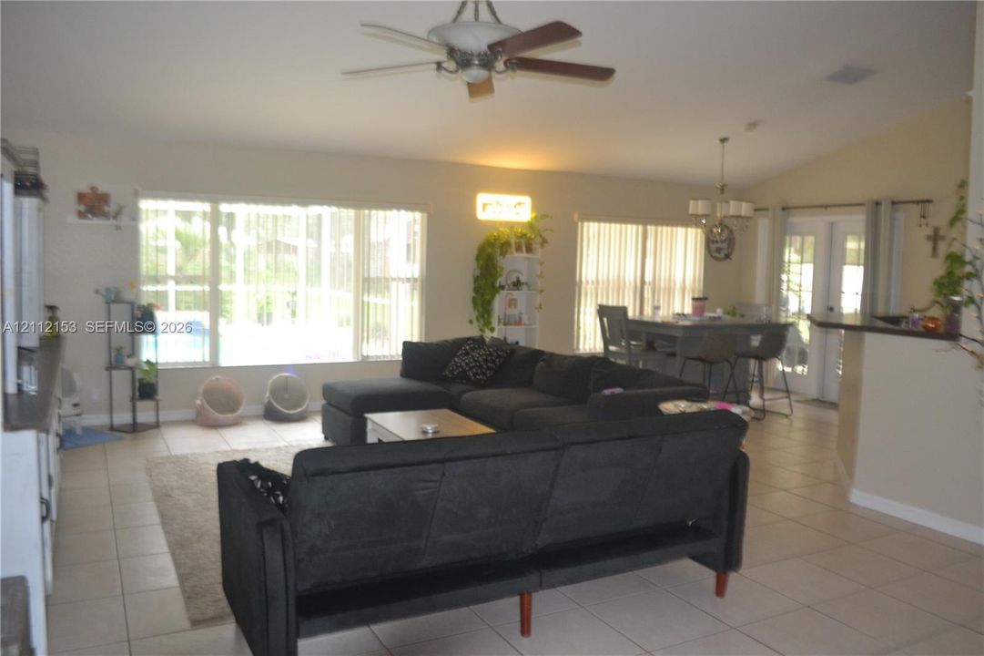 Open-concept interior featuring large-format ceramic tile flooring, vaulted ceilings, a ceiling fan, and extensive windows