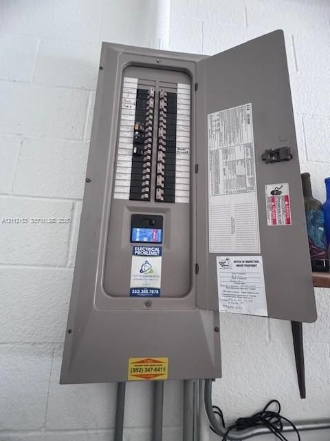 Electrical service panel with labeled breakers, mounted on a painted concrete block wall