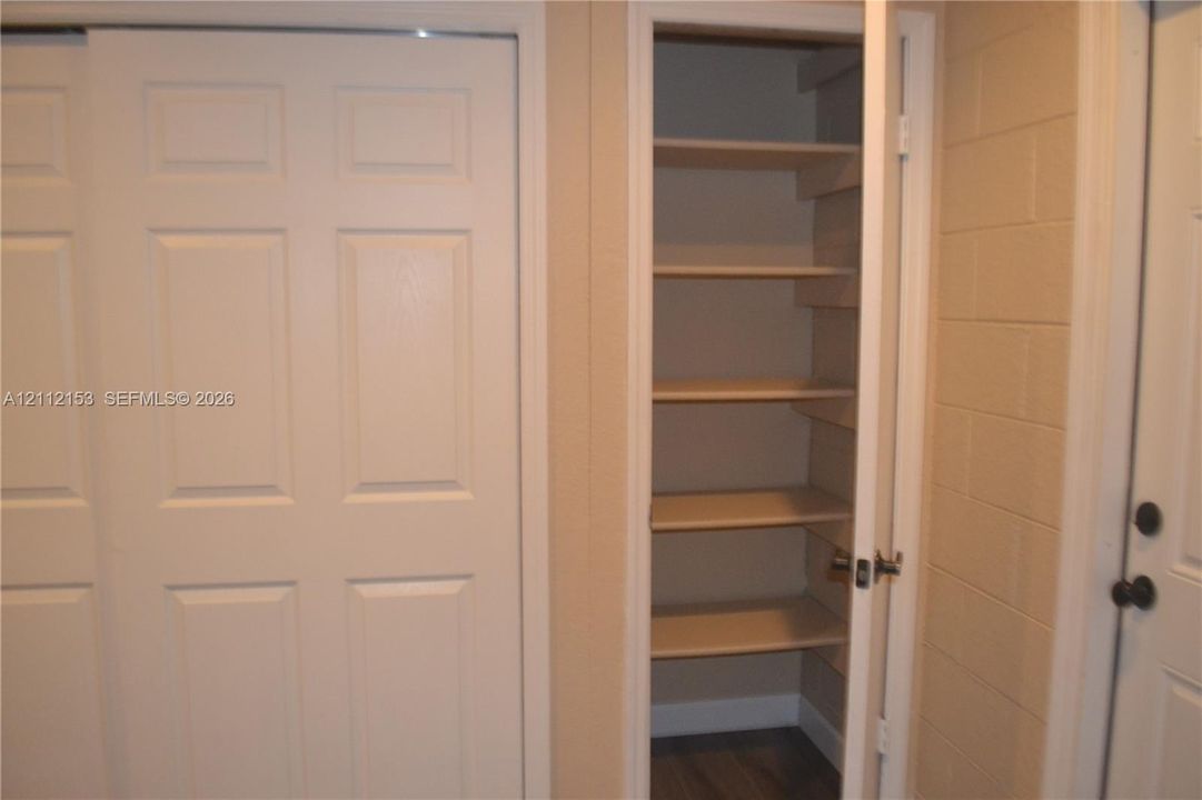 Built-in storage closet with six shelves, six-panel sliding door, and neutral-finish walls