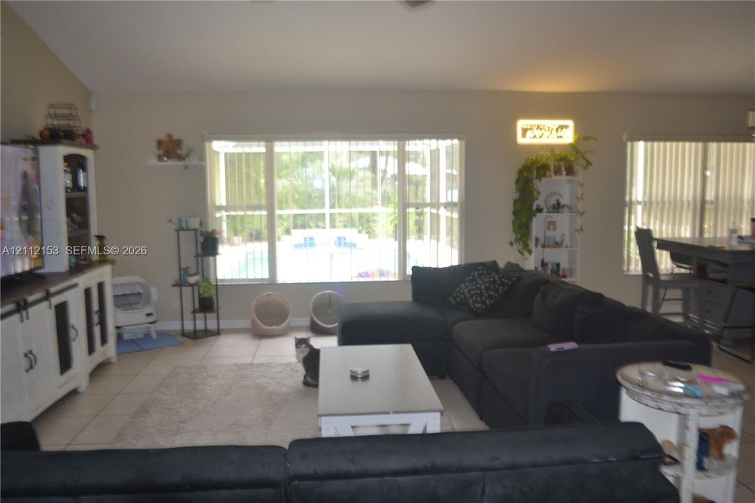 Open-concept interior featuring high vaulted ceilings, large picture windows, tile flooring, and built-in cabinetry
