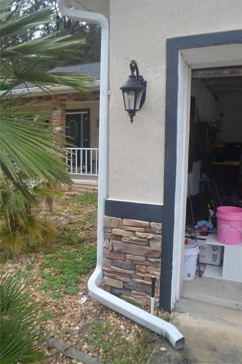 Exterior elevation featuring textured stucco siding with stacked stone veneer accents, contrasting dark trim, and a wall-mounted lantern-style light fixture