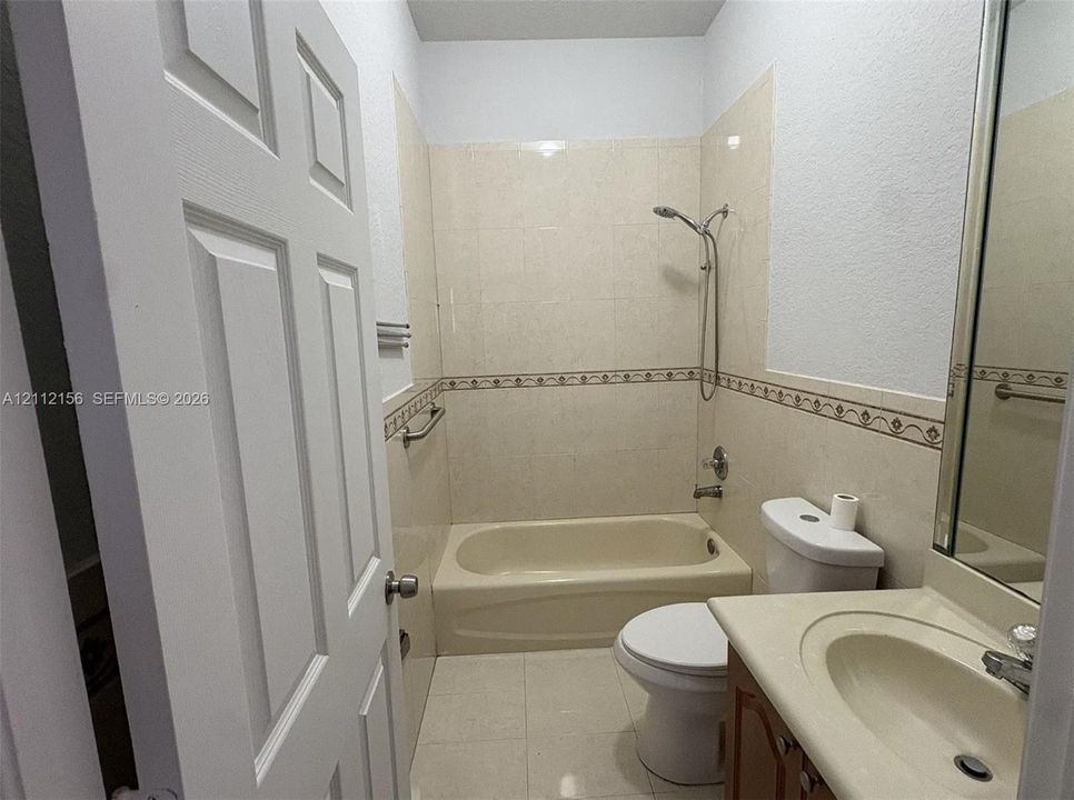 Bathroom featuring a soaking tub, tile surround with decorative inlay, integrated vanity with a molded basin, and chrome fixtures
