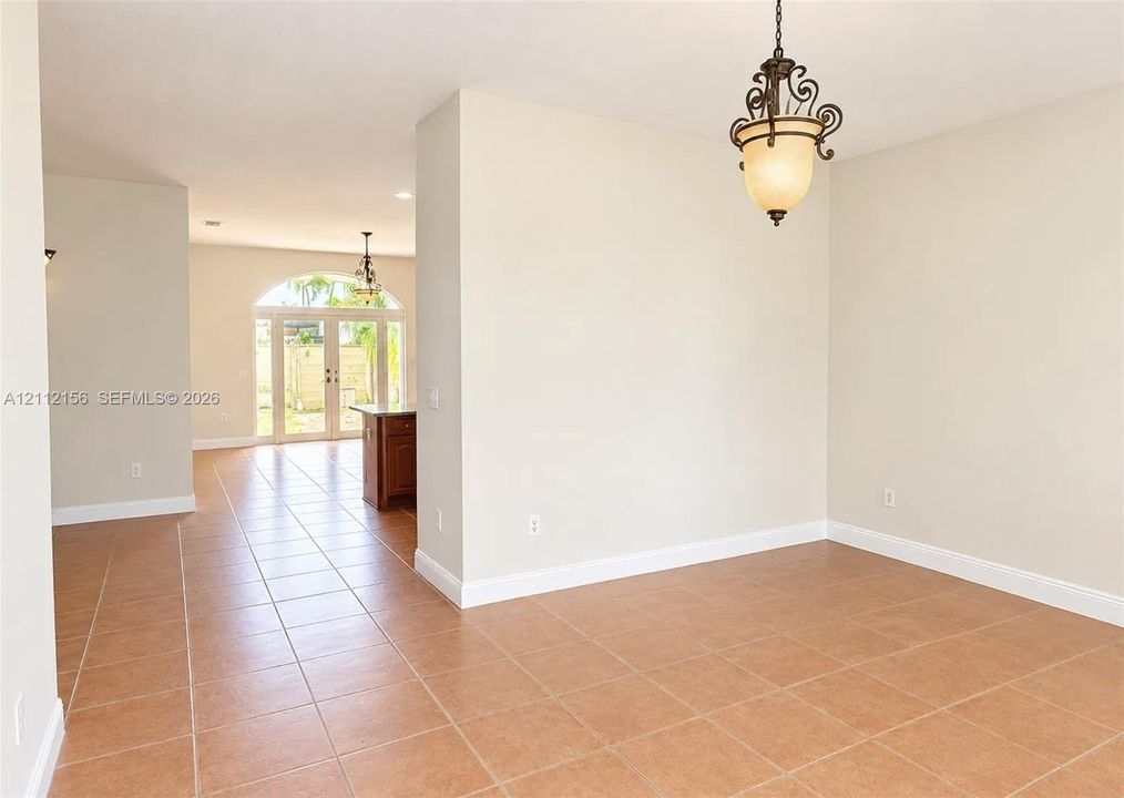 Neutral-toned interior featuring ceramic tile flooring, arched glass double doors, and decorative pendant lighting