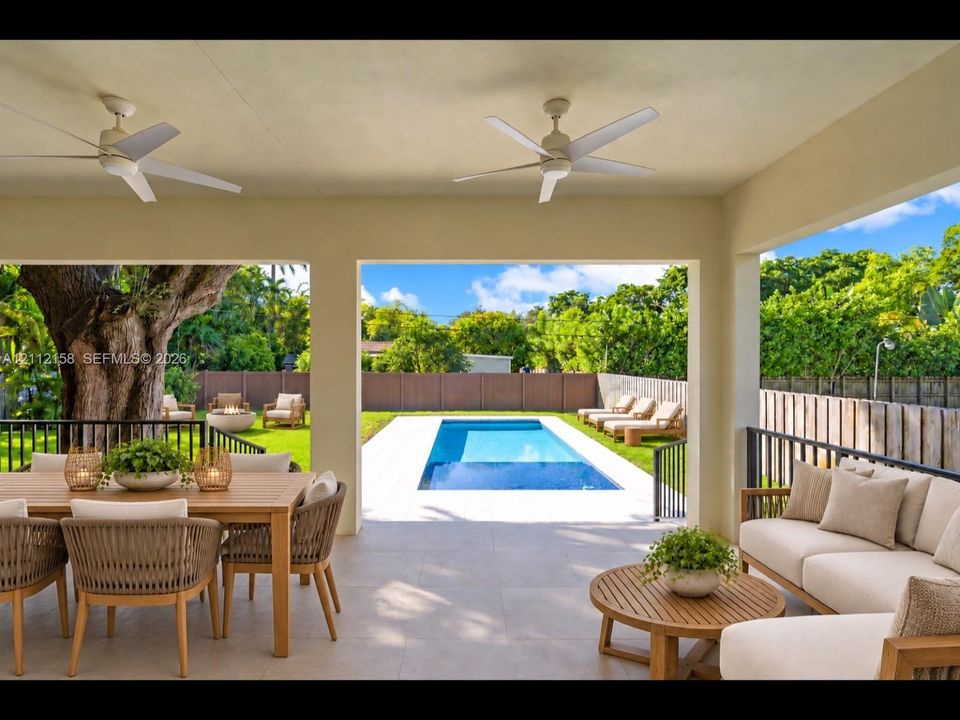 (Digitally staged) Spacious covered patio with stone-look tile and ceiling fans, overlooking the rectangular pool — ideal for entertaining or relaxing in the shade