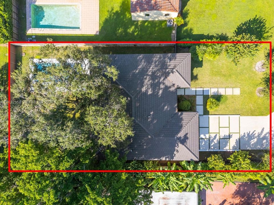 Aerial view showcasing the private pool, paver walkway, and lush, mature landscaping surrounding the home