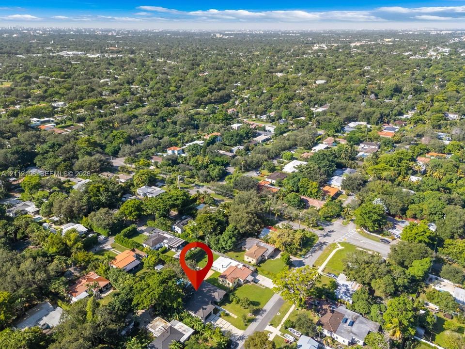 Aerial view of the property on a generous lot with a paved driveway and mature trees in a quiet, low-density neighborhood