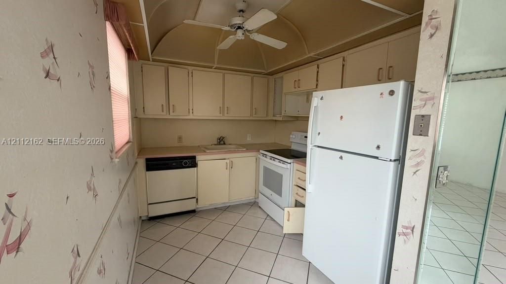 Kitchen featuring cabinetry with neutral-finish doors, solid-surface countertops, tile flooring, and ceiling-mounted fan