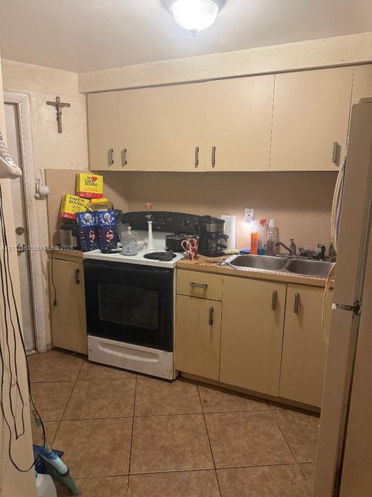Kitchen featuring flat-panel cabinetry, dual-basin stainless steel sink, tiled flooring, and ceiling-mounted light fixture