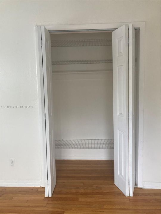 Closet featuring white six-panel bi-fold doors, white wire shelving, and wood-finish flooring