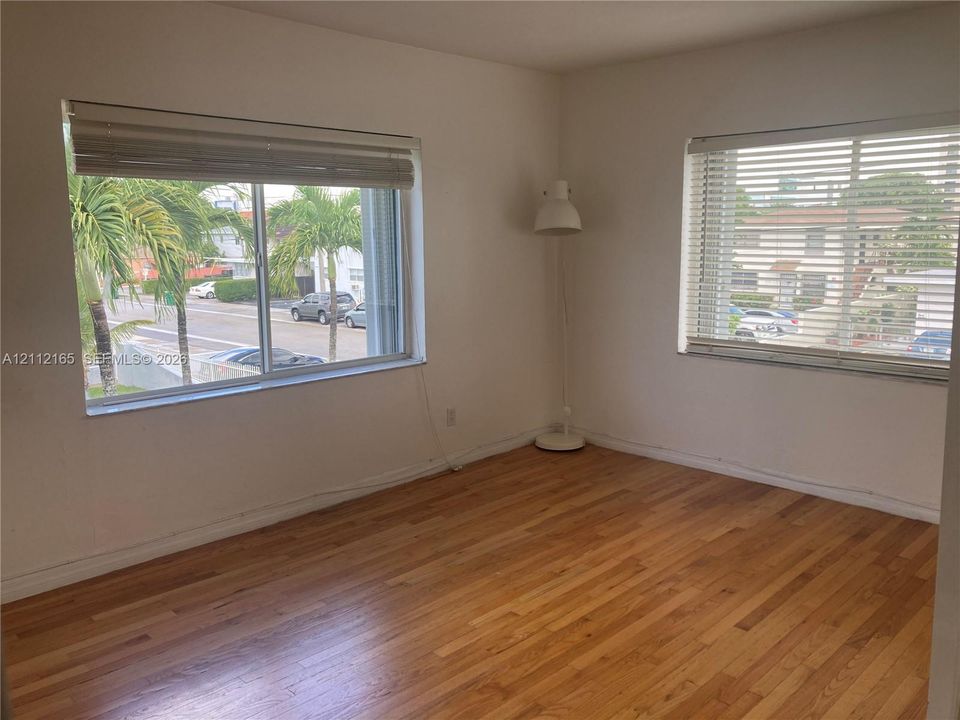 Interior room featuring wood-finish flooring, two large windows, and horizontal blinds