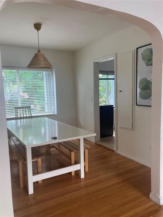 Arched doorway, wood-finish flooring, built-in wall cabinetry, and hanging pendant lighting