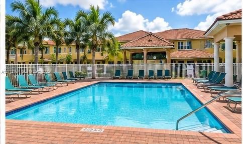 Swimming pool featuring brick paver decking, a covered pavilion, and mature palm trees