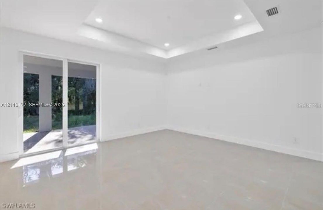 Interior space featuring a recessed tray ceiling, recessed lighting, polished tile flooring, and sliding glass doors