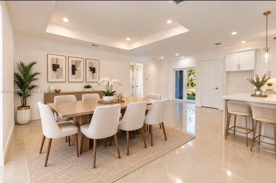 Tray ceiling with recessed lighting, large-format tile flooring, white shaker-style cabinetry, and pendant lighting