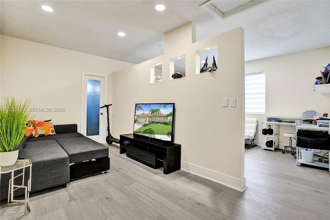 Interior space featuring wood-finish flooring, recessed lighting, and a partial partition wall with built-in decorative niches
