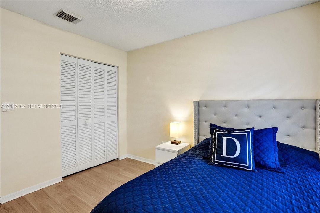 Neutral-toned walls, wood-finish flooring, and a closet with white louvered bifold doors